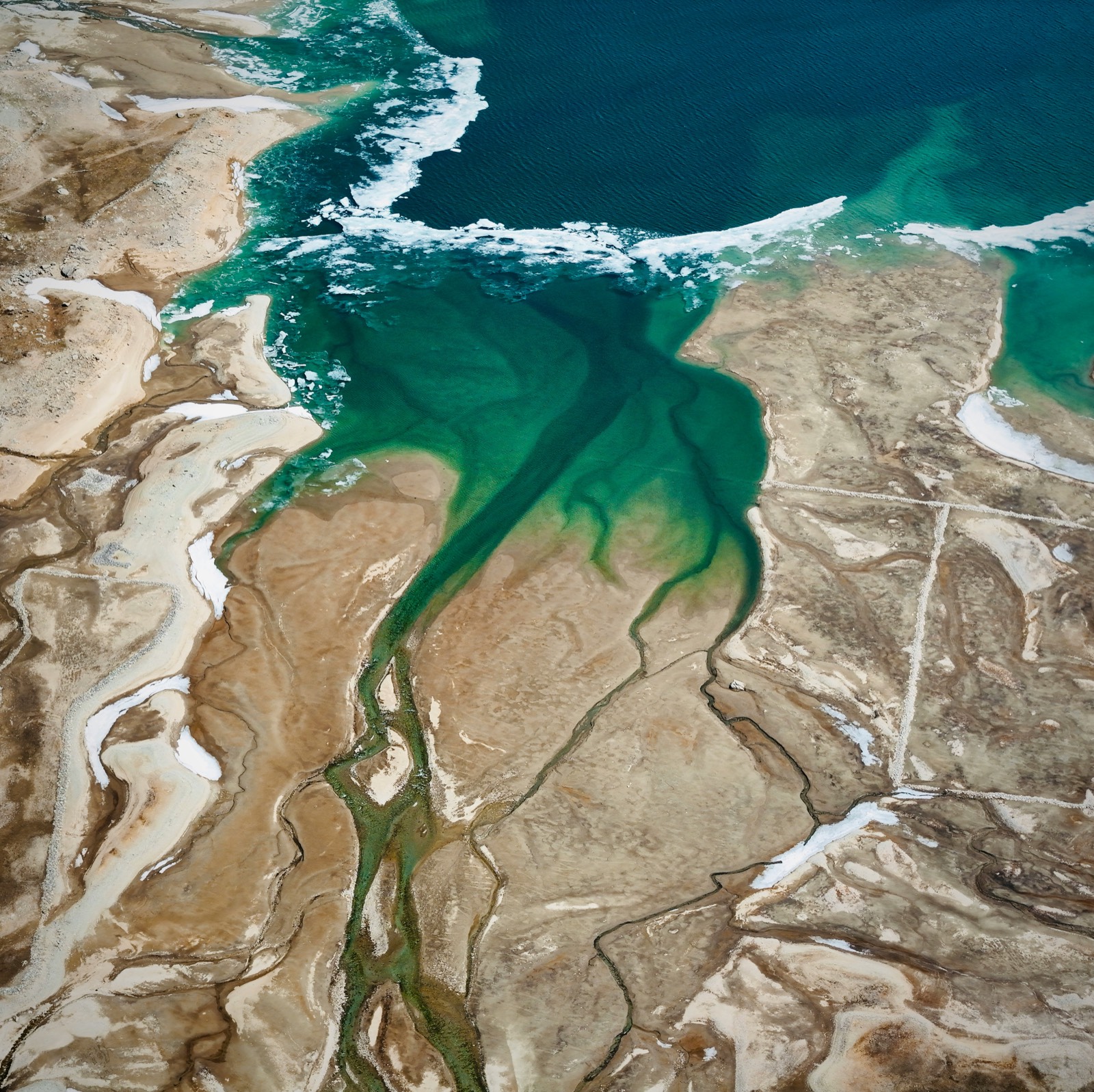 Aerial view of a river delta meeting a turquoise sea